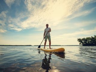 A Man Paddle Boarding On A Lake